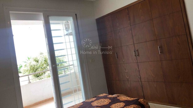 Une chambre à coucher comprenant un lit, une armoire et une porte-fenêtre coulissante donnant sur un balcon.