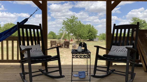 A wooden deck with two rocking chairs, a small table with a kettle and cups, and a hammock. - Sunrise Sunset Peaceful Country Cabin  (Bruceville)