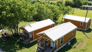 A small, single-story wooden cabin with a porch and a covered outdoor seating area. - Sunrise Sunset Peaceful Country Cabin  (Bruceville)