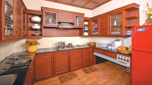 Une cuisine avec des meubles de rangement en bois, une cuisinière et un réfrigérateur.
