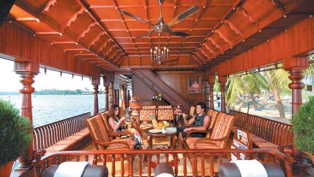 Une terrasse en bois offrant une vue sur l’eau, aménagée avec des canapés et une table.