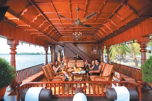 Une terrasse en bois offrant une vue sur l’eau, aménagée avec des canapés et une table.