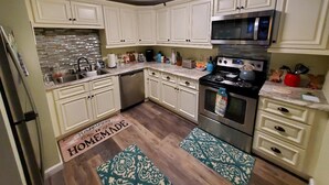 A kitchen with white cabinets, a stainless steel stove, a microwave, and a dishwasher. - Beautiful condo right near all North Conway, Jackson and Bartlett has to offer! (Bartlett)