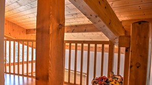 A wooden interior with a high ceiling, a balcony with a railing, and a wicker basket with toys.