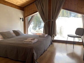 Ein Schlafzimmer mit einem großen Bett, einem Sessel und einem Fenster mit Vorhängen.
