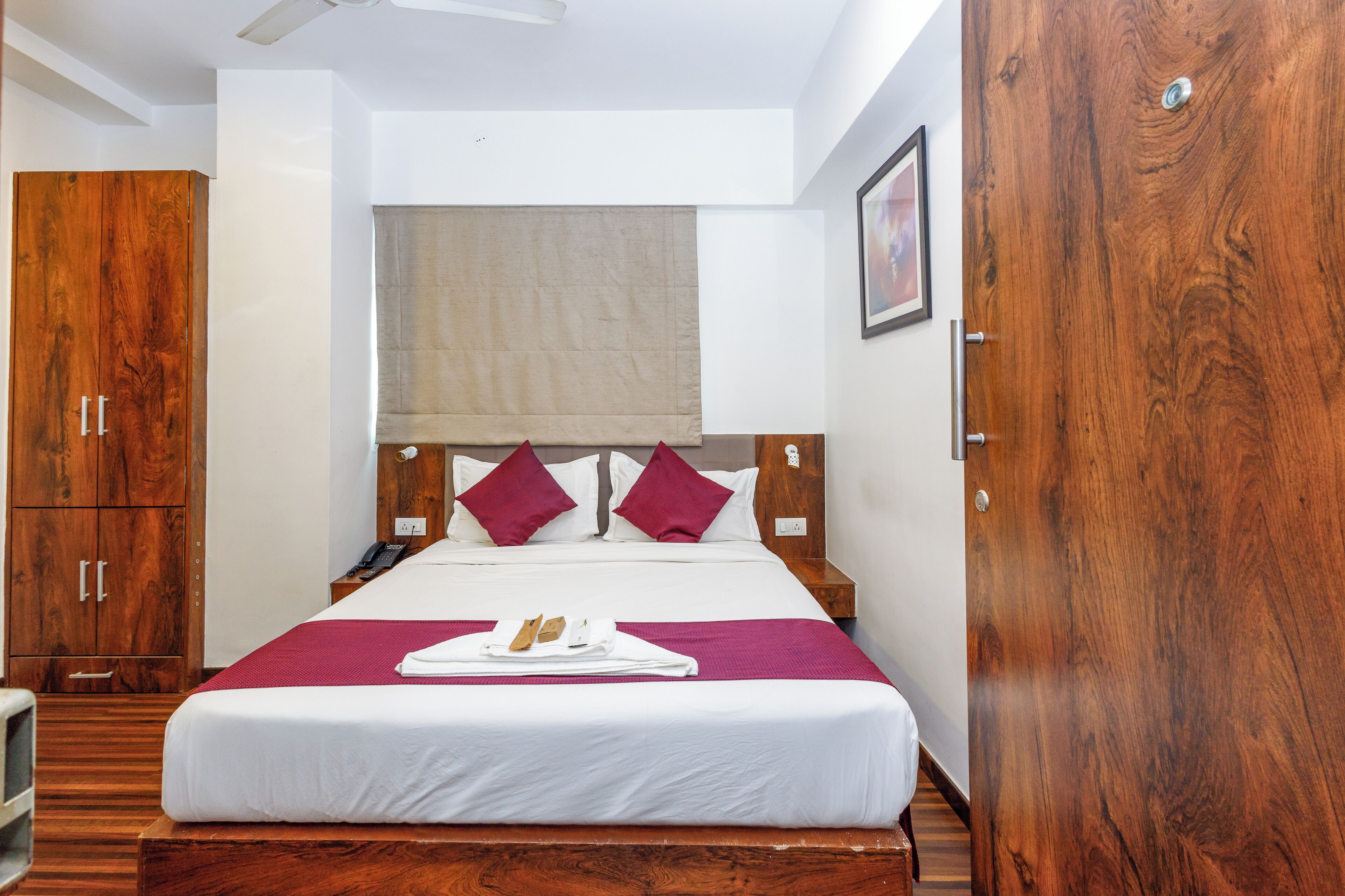 Habitación de hotel con una cama grande, un armario de madera y un ventilador de techo.