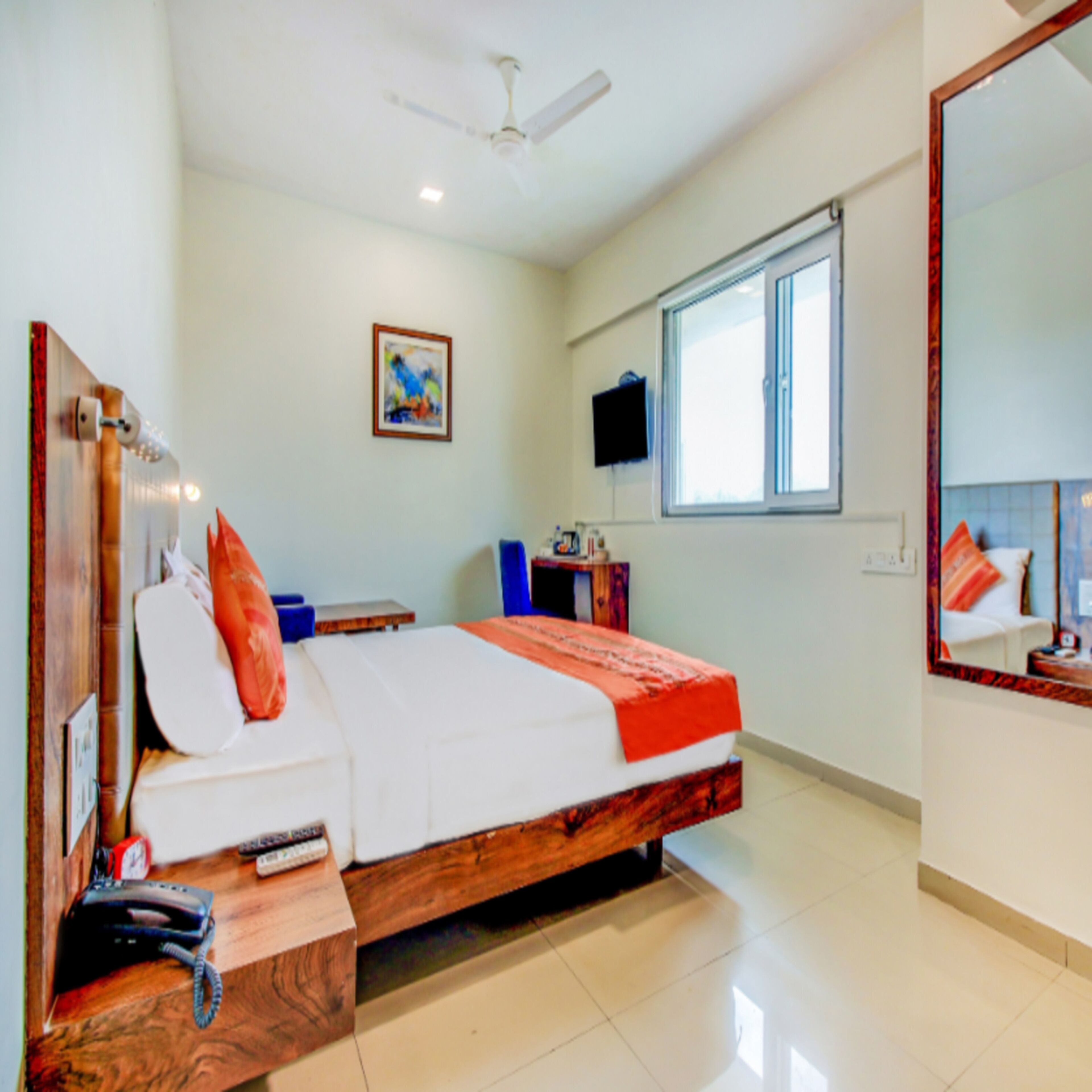 Un dormitorio con cama, escritorio, silla, televisor y ventana.