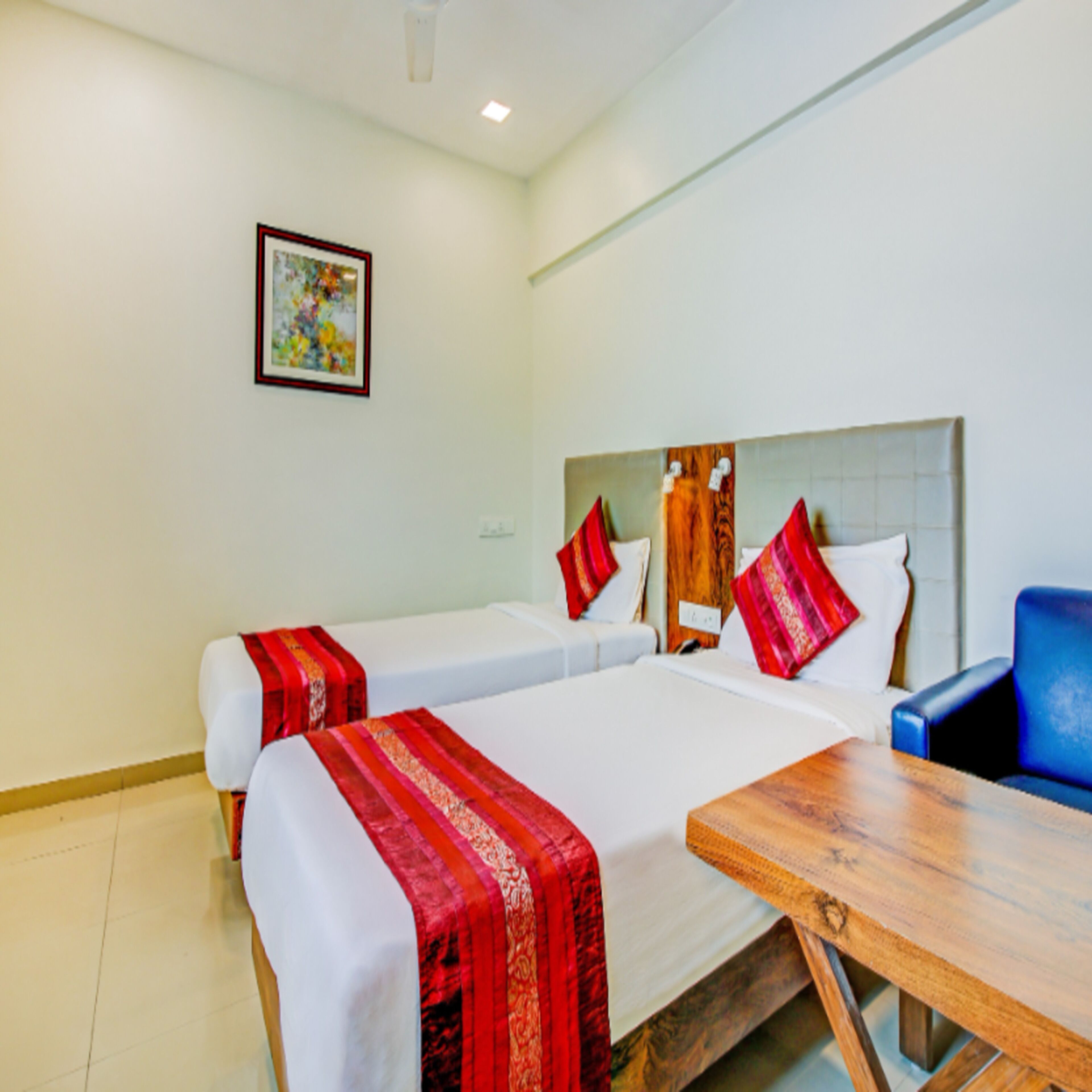 A hotel room with two beds, a wooden table, and a blue chair.