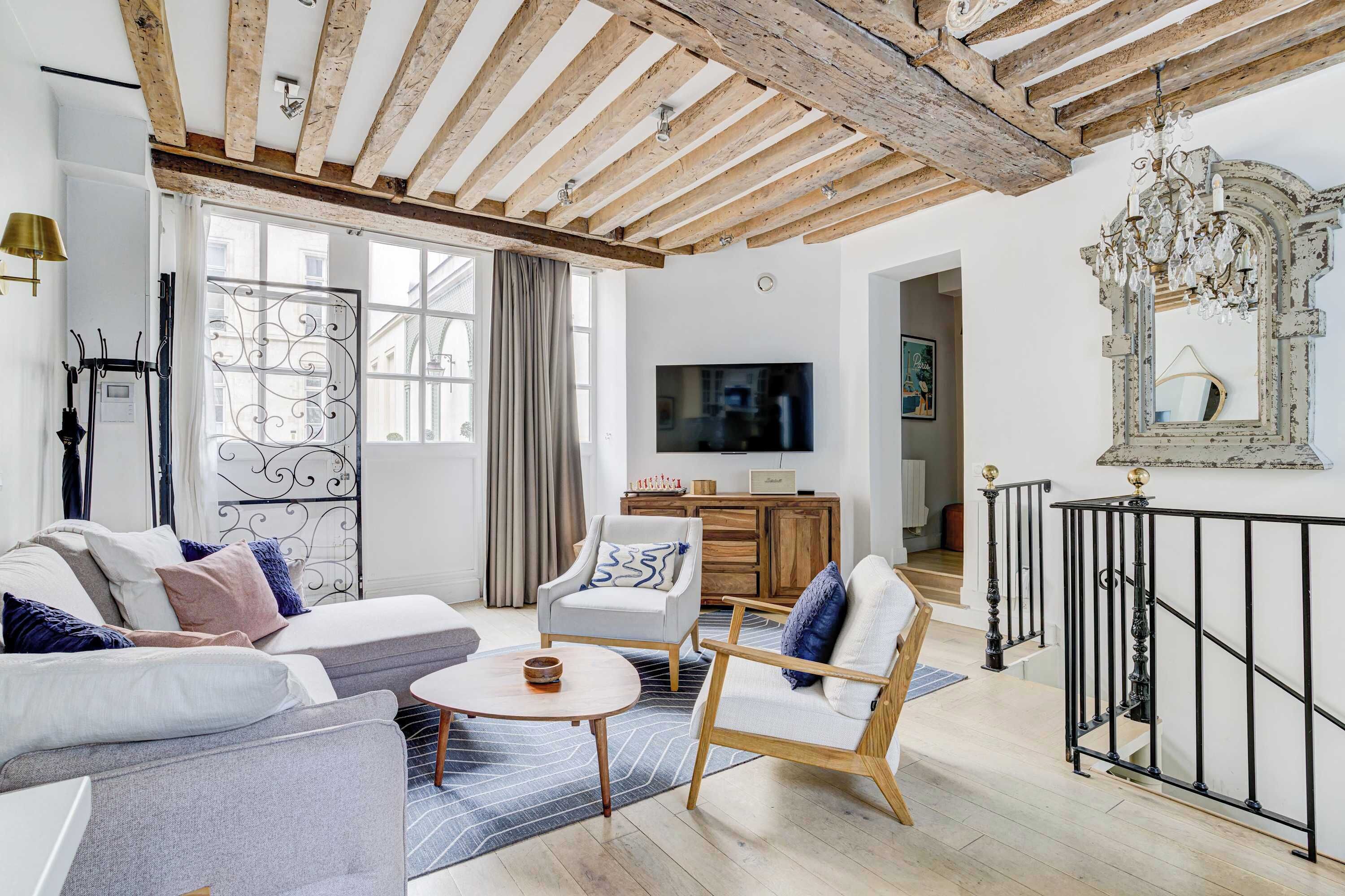 A modern living room with exposed wooden beams, a sofa set, a coffee table, and a TV.