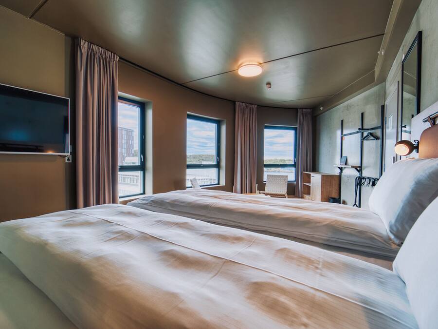Een hotelkamer met twee bedden, een televisie, een bureau en uitzicht op de stad.