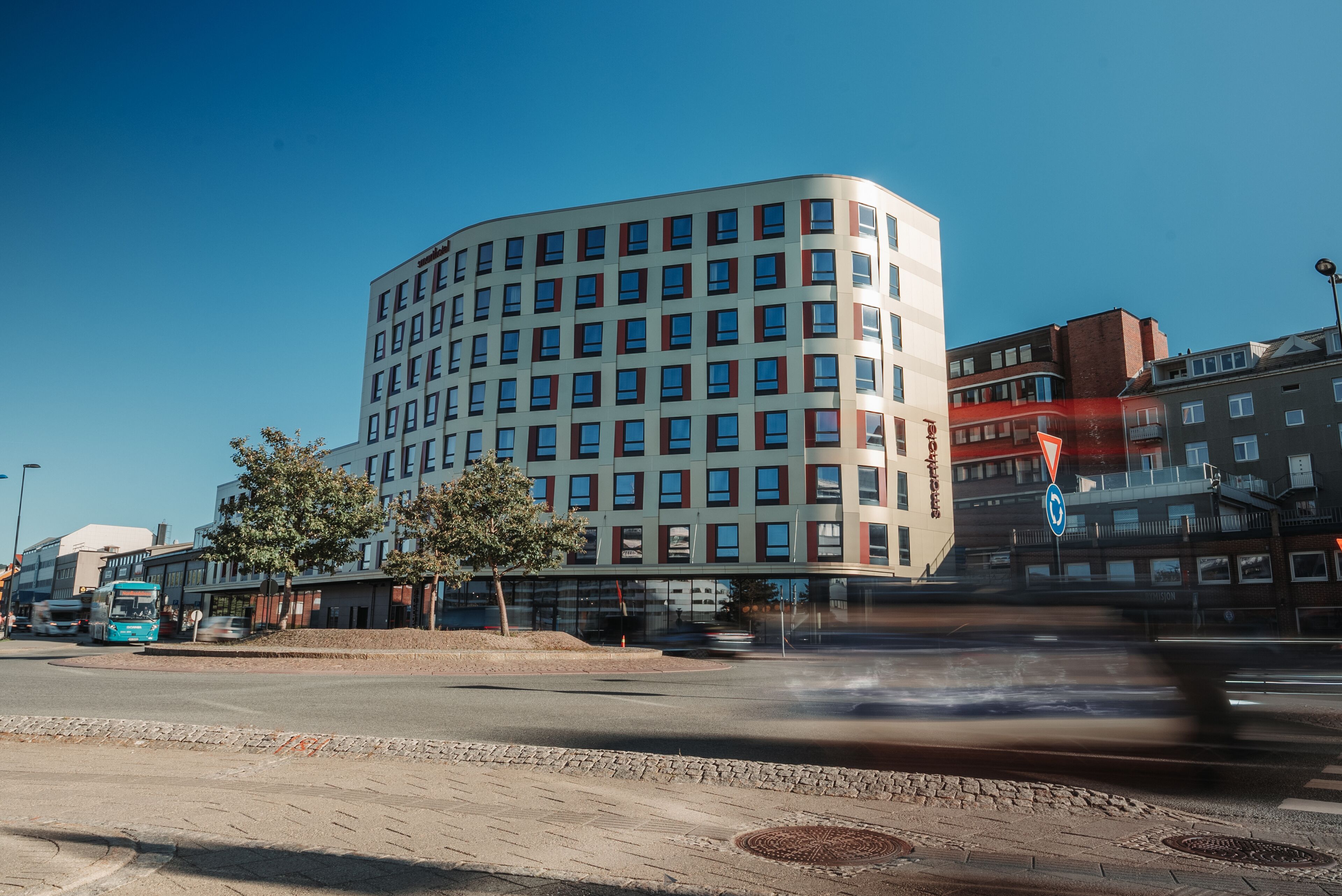 A modern building with a curved facade, multiple windows, and a visible entrance.
