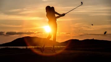 Silueta de una persona jugando al golf al atardecer.