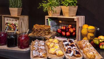 Una mesa de buffet con diversos alimentos, como pasteles, frutas y salsas.