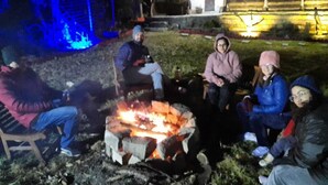 A group of people sitting around a fire pit in an outdoor setting.