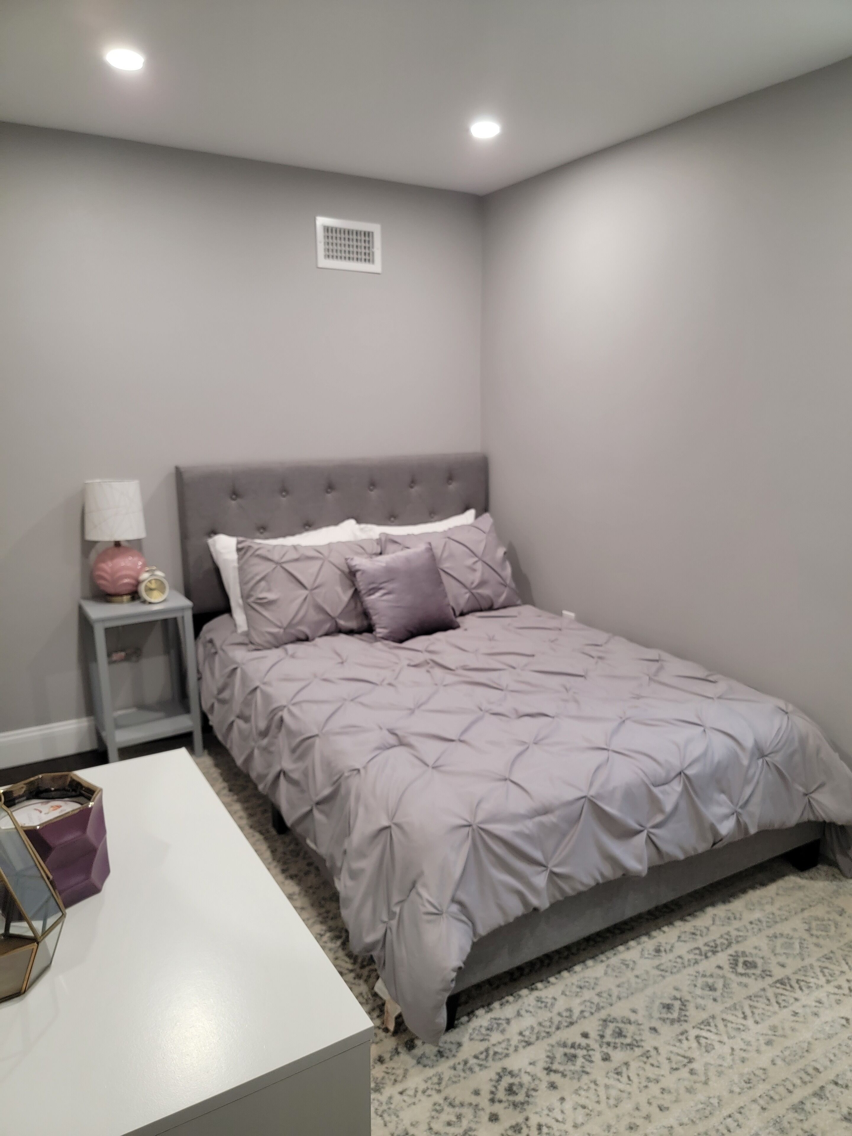 A bedroom with a bed, a nightstand, a lamp, and a small table.