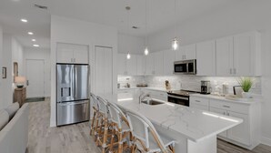 A modern kitchen with white cabinetry, stainless steel appliances, and a marble island. - GULF PLACE-STUNNING CONDO OFF 30A!! 3 BED/3 BATH!! SLEEPS 6!! (Santa Rosa Beach)