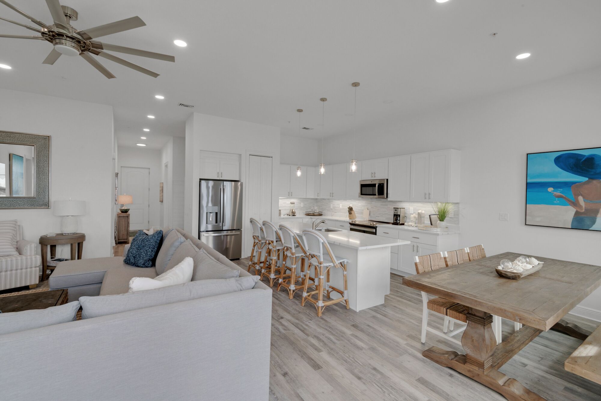 A modern kitchen with white cabinets, a stainless steel refrigerator, and a central island with bar stools.