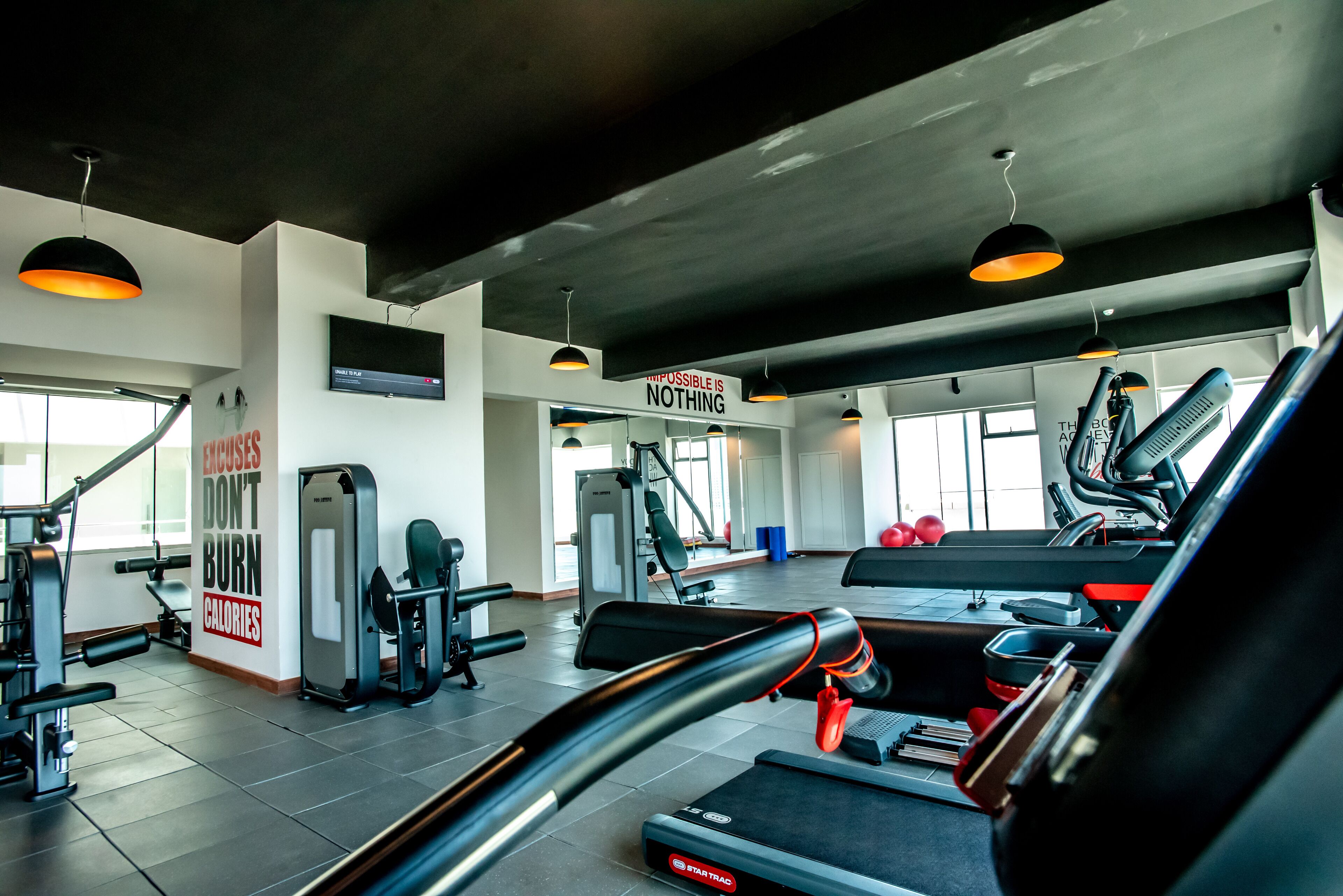 A gym with treadmills, weight machines, and a motivational quote on the wall.