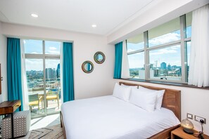 Ein Hotelzimmer mit einem großen Bett, einem Balkon mit Blick auf die Stadt und zwei runden Spiegeln an der Wand.