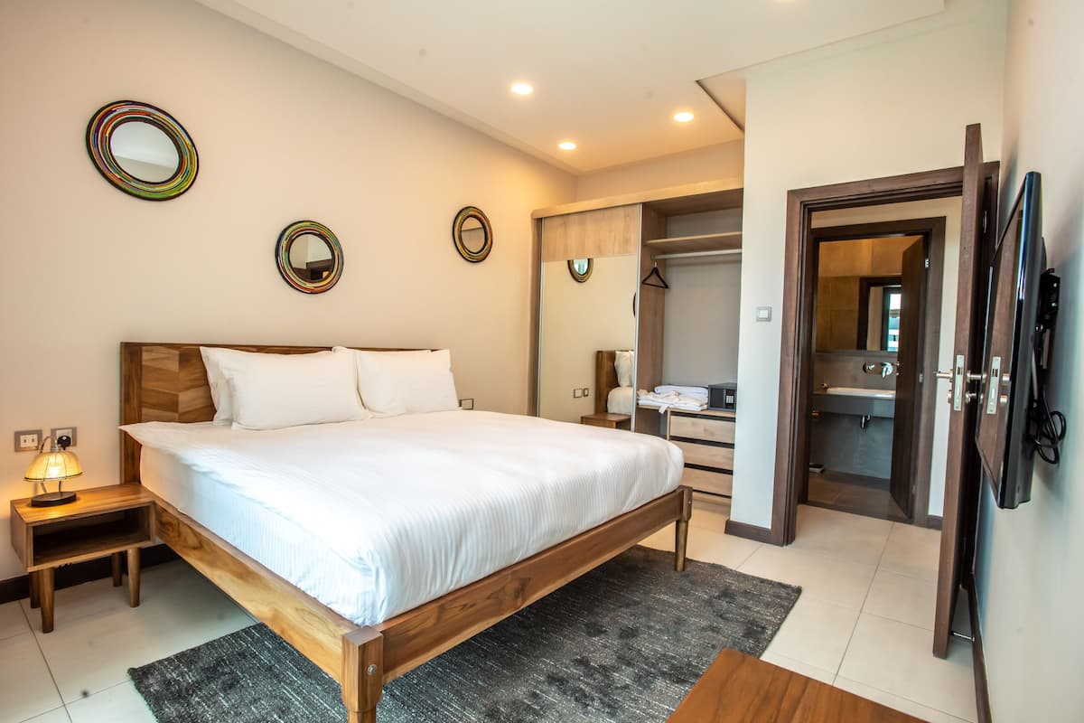Une chambre à coucher comprenant un lit, des tables de chevet, un miroir et un dressing.