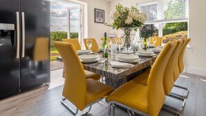 A dining area with a black refrigerator, yellow chairs, a marble table, and a vase of flowers. - Routhorpe House (Driffield)
