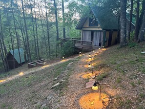 A cabin with a porch, surrounded by a forest.