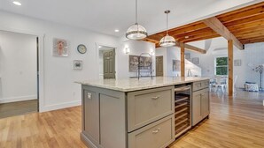 A spacious kitchen with a large island, wooden beams, and pendant lighting.