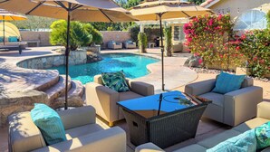 An outdoor patio area with a pool, comfortable seating, and umbrellas.