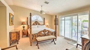 A spacious bedroom with a four-poster bed, a ceiling fan, and a large sliding glass door leading to an outdoor area.