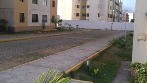 A residential street with multi-story buildings, a paved sidewalk, and small plants along the curb. - APARTMENT NEAR SKYSURF CUMBUCO IN CAUCAIA (CAUCAIA)