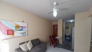 A living room with a gray sofa, a ceiling fan, and a painting on the wall. - APARTMENT NEAR SKYSURF CUMBUCO IN CAUCAIA (CAUCAIA)