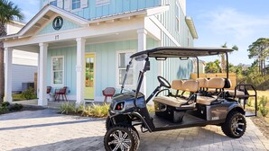 Un carrito de golf estacionado frente a una casa azul claro con un letrero con el número 17.