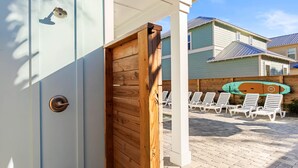 Puerta de madera que da a un espacio exterior cubierto con sillones de descanso y una decoración de tabla de surf.