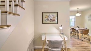 A modern interior with a staircase, a glass desk, a chair, a dining area, and a framed artwork on the wall. - Mid-Century Bozeman Townhome ~ 1 Mi to Dtwn! (Bozeman)