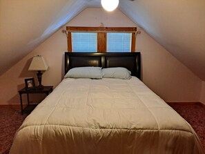 Cozy retreat with a single bed, bedside table, and lamp, set against a sloping ceiling.