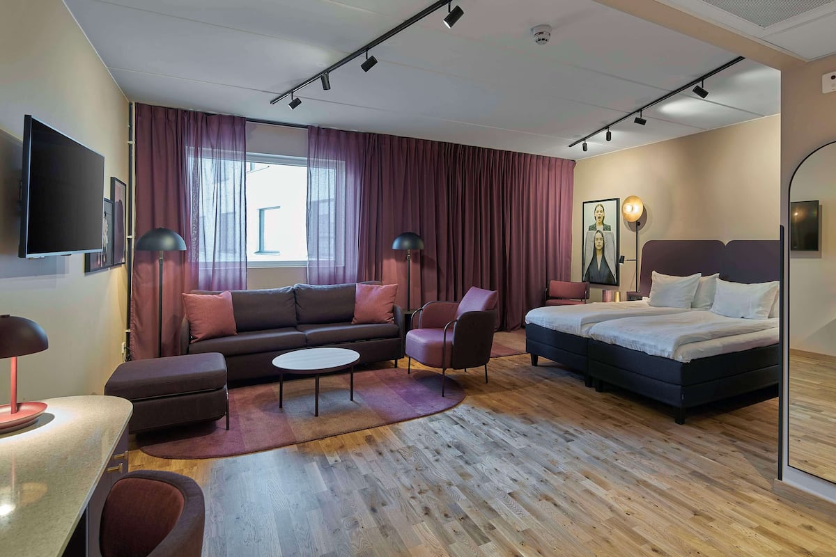 Une chambre d’hôtel moderne équipée d’un grand lit, d’un canapé, d’un bureau et d’une télévision.