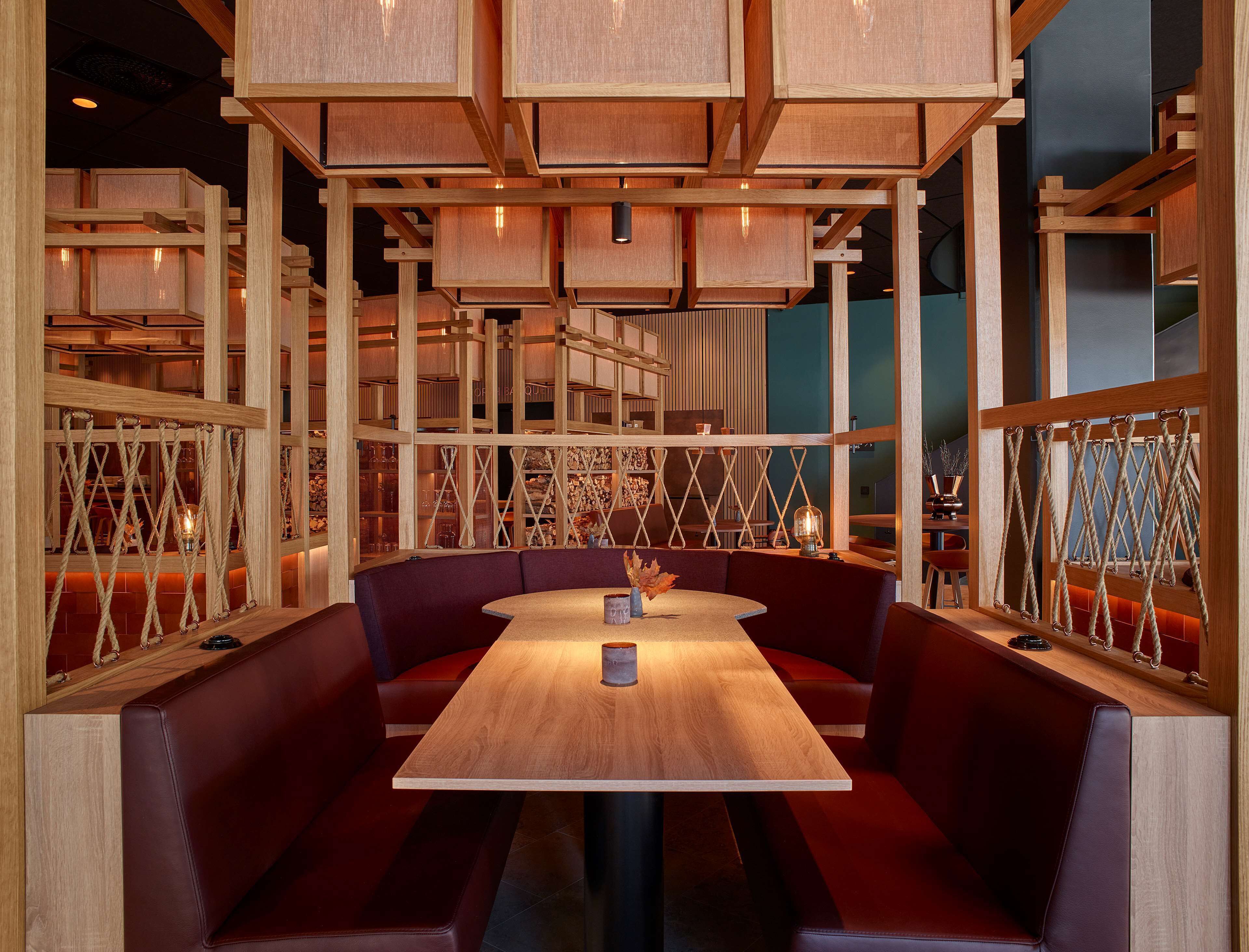 A restaurant interior with wooden paneling, cushioned booths, and a central table.