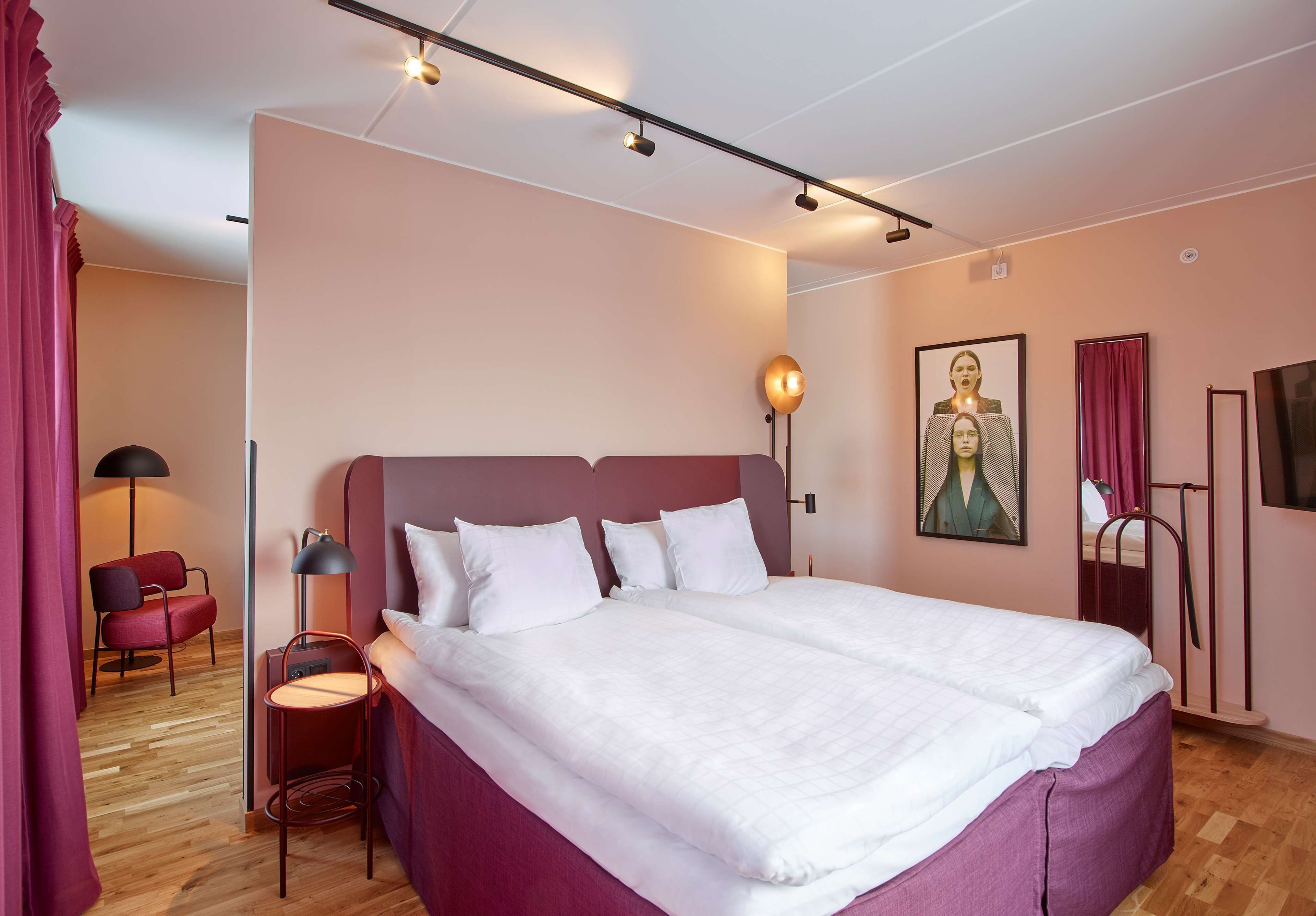 Ein modernes Hotelzimmer mit einem großen Bett, einem Schreibtisch, einem Sessel und einer Lampe.