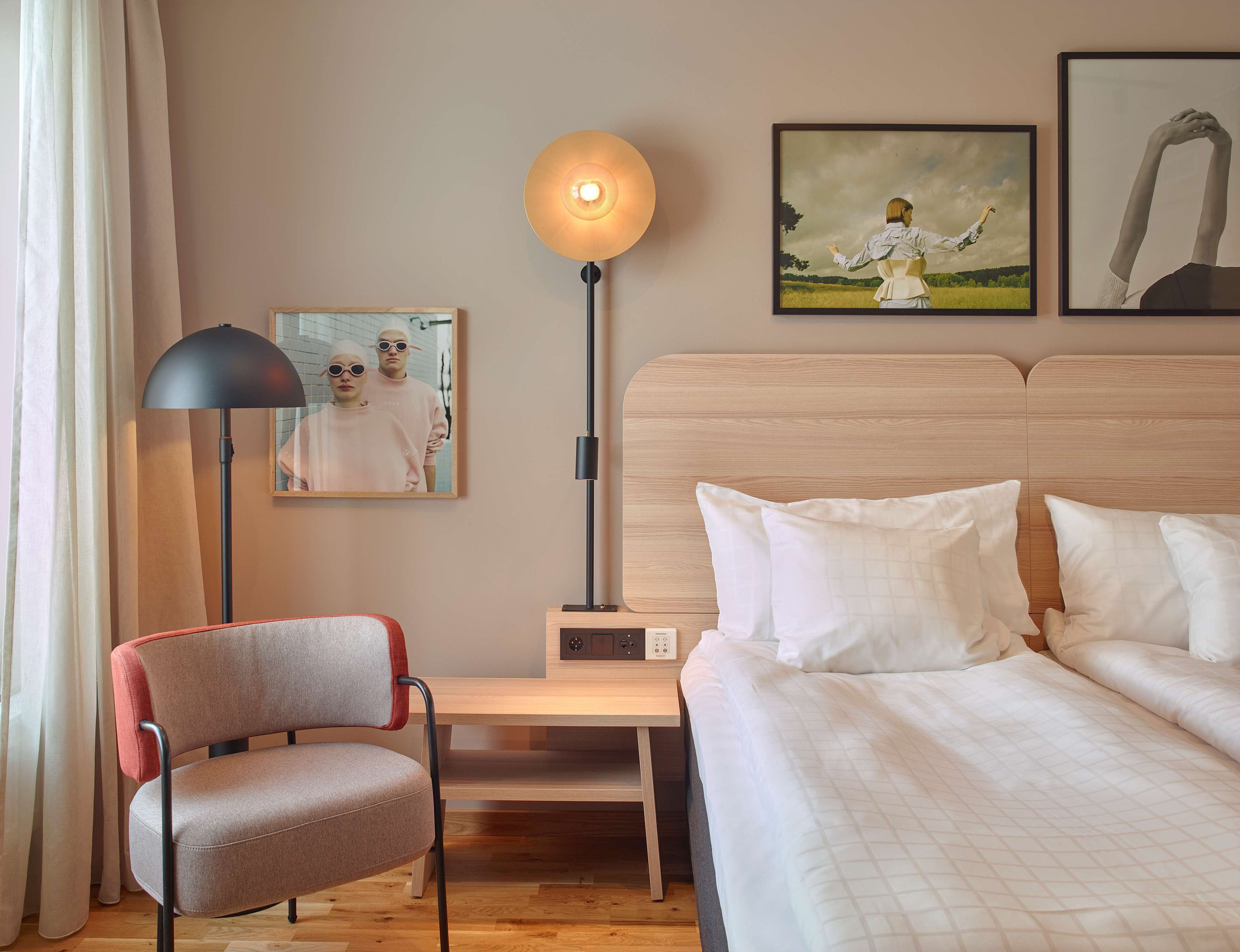 Et hotelværelse med en seng, en stol, et natbord, en lampe og to billeder hængende på væggen.