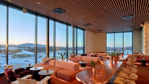 Un salón moderno con ventanas amplias, techo de madera y vista a un paisaje nevado.