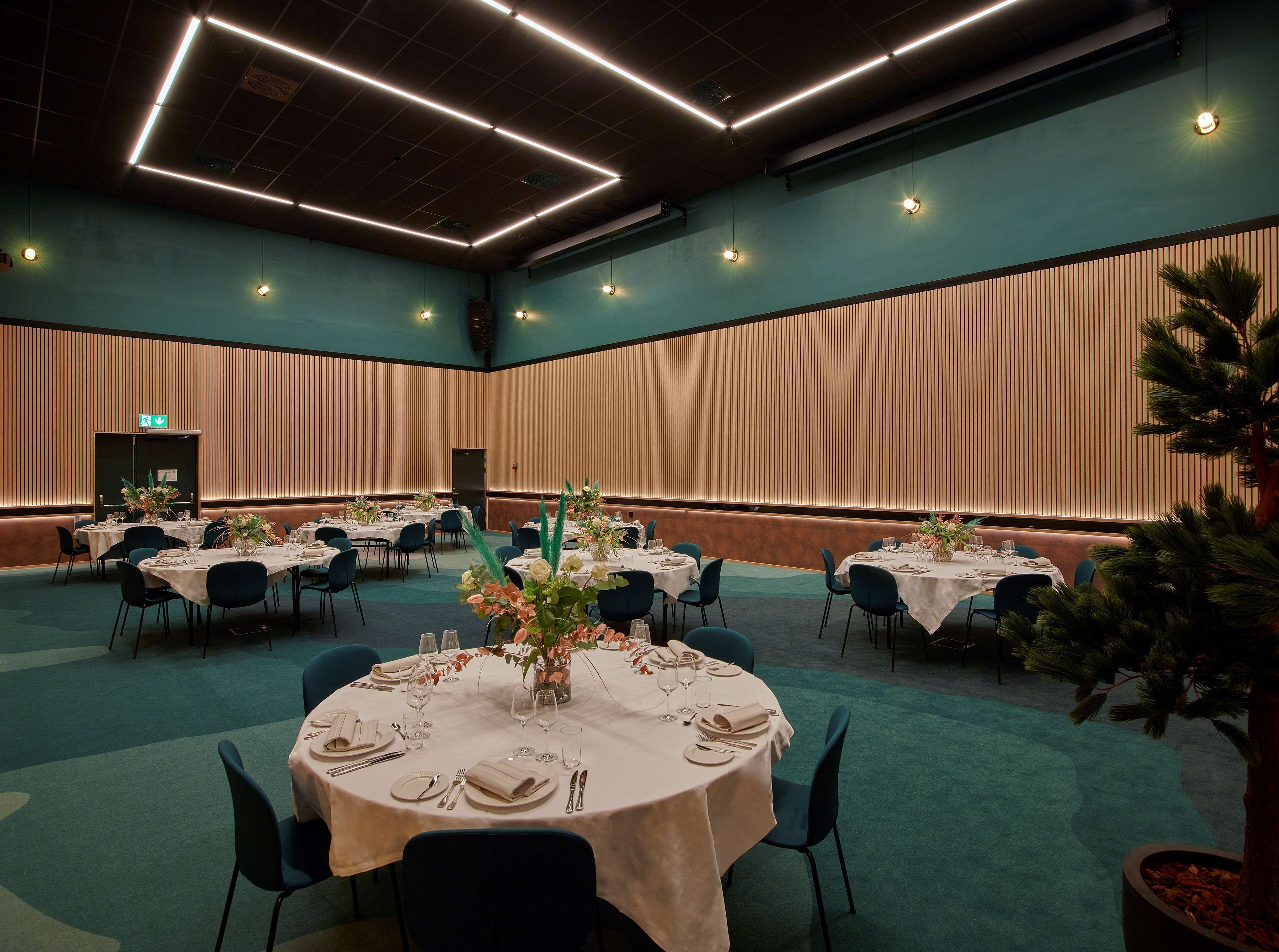A conference room with round tables set for dining, equipped with chairs and table settings.