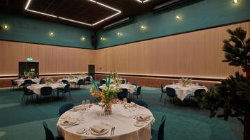 A conference room with round tables set for dining, equipped with chairs and table settings.