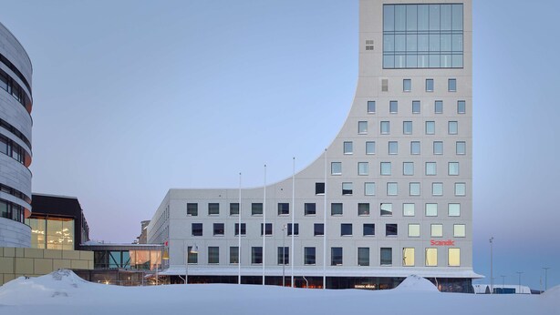 Un edificio moderno con fachada curva, varias ventanas y un letrero Scandic.