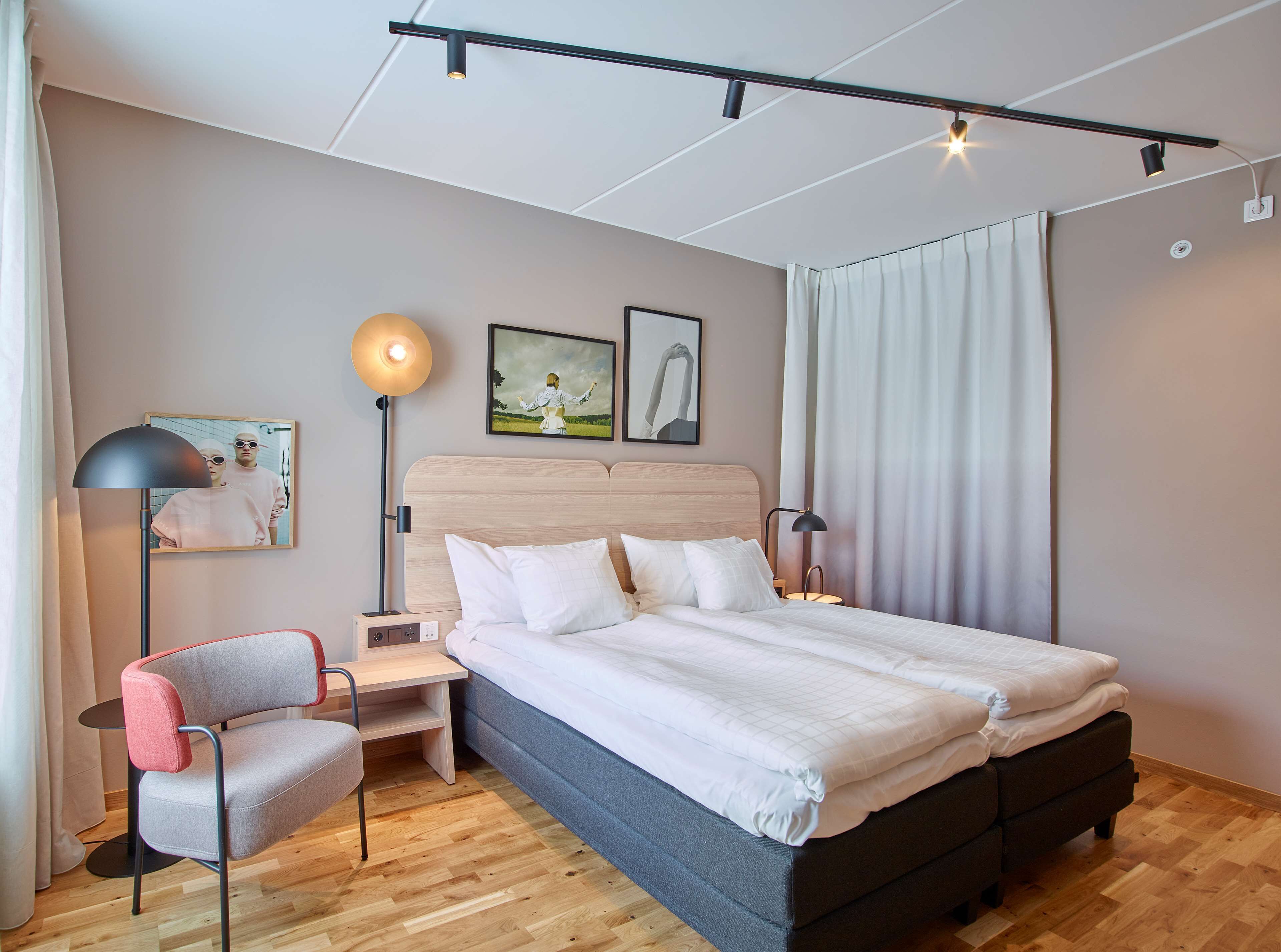 A modern bedroom with a large bed, a desk, a chair, and two bedside lamps.