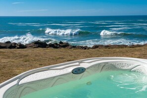Relax in a hot tub overlooking the ocean with waves gently crashing on the shore.