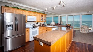 A modern kitchen with stainless steel appliances, wooden cabinets, and a large island. - Promo! Oceanfront Condo with Private Hot Tub, Indoor Pool, Wifi and HDTV! (Depoe Bay)