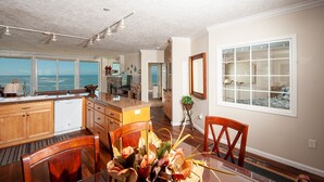 A spacious kitchen with a view of the ocean, wooden cabinets, and a dining area with a table and chairs. - Promo! Oceanfront Condo with Private Hot Tub, Indoor Pool, Wifi and HDTV! (Depoe Bay)
