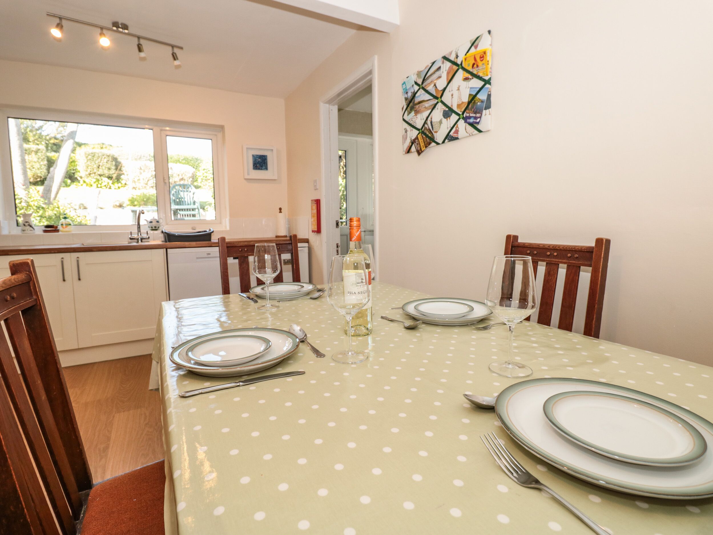 A dining area with a polka dot tablecloth, wooden chairs, and a glass of white wine.