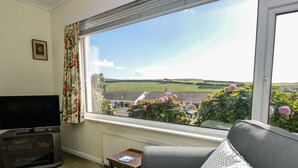 A living room with a television, a small table, a sofa, and a window with a view of a green landscape. - 33 Weymouth Park (Kingsbridge)