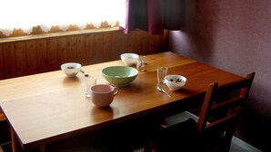 A wooden dining table with four bowls, a glass, and a mug. - 4-PERSON STUDIO AT THE FOOT OF THE NORDIC SKI SLOPES (BESSANS)